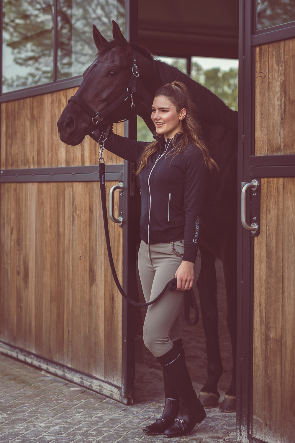 kristy snepvangers poseert in de kleding van horka met een paard dat tussen twee schuifdeuren staat